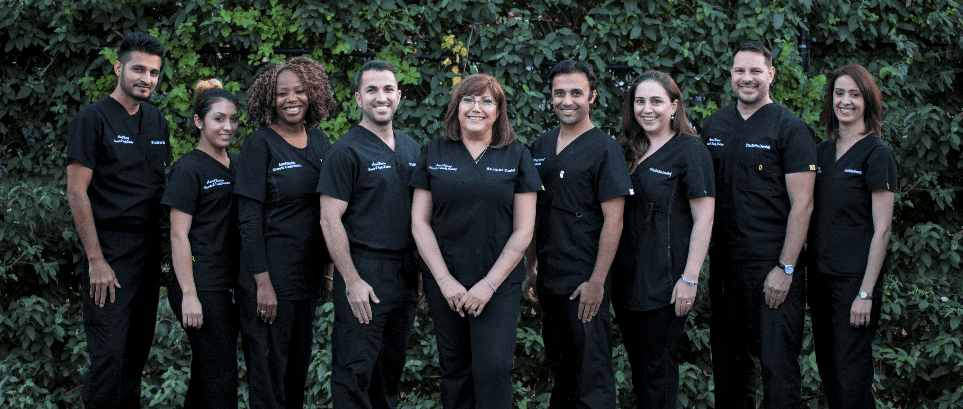 A group of people wearing black scrubs are posing for a picture.